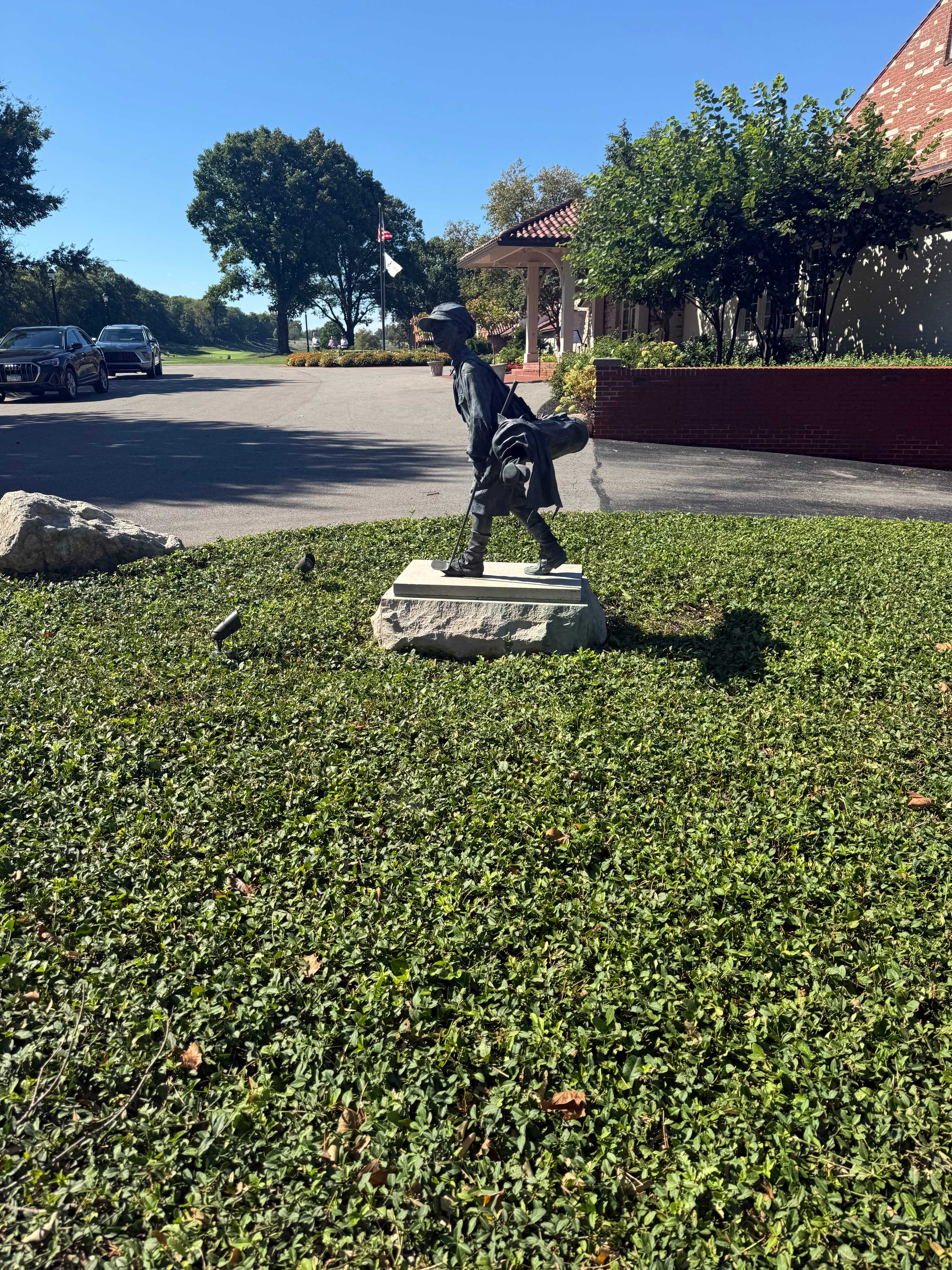 A bronze caddie statue on the clubhouse lawn