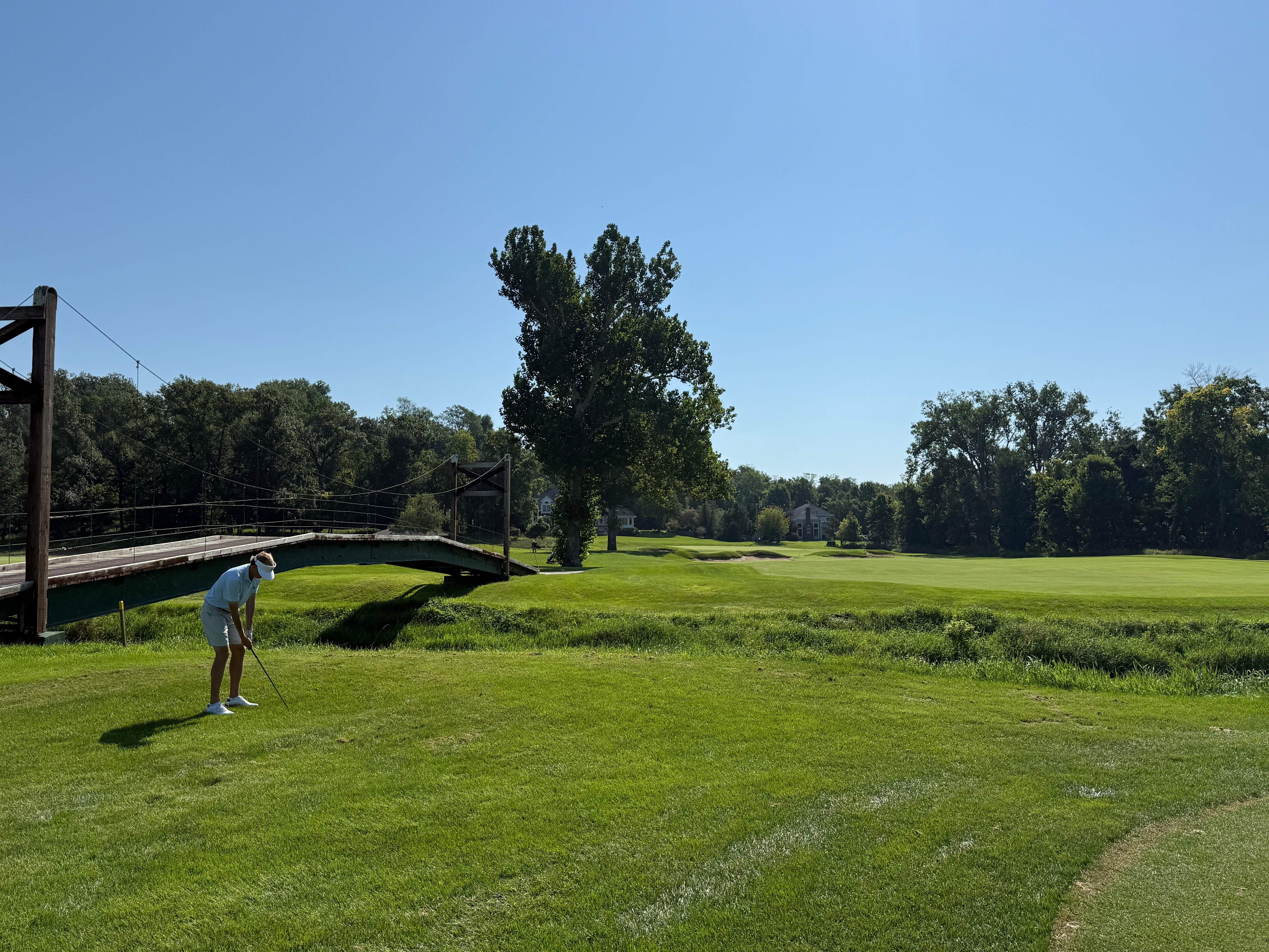 A golfer beside the bridge crossing Indian Creek on the sixth hole